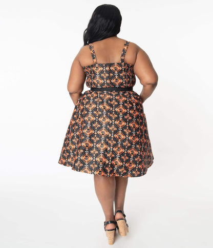 This is a Unique Vintage Halloween swing dress that has black cats, bats and skulls with orange print and the plus model is wearing black shoes and a belt.